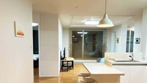 Une cuisine moderne avec un îlot central, un plancher en bois et un luminaire suspendu.