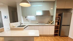 Eine moderne Küche mit einer zentralen Kochinsel, weißen Schränken und einem Edelstahlkühlschrank.