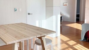 Un intérieur moderne avec une table à manger en bois, des chaises blanches et une porte blanche.