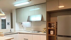 Une cuisine moderne avec des meubles blancs, un réfrigérateur en acier inoxydable et un plancher en bois.