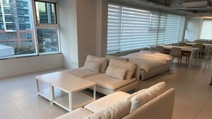 A modern living room with a sectional sofa, a coffee table, and a dining area with chairs and tables.