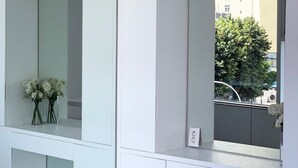 A modern, minimalist room with a large mirror, a small table, and a chair. There are two vases with flowers on the mirror's surface.