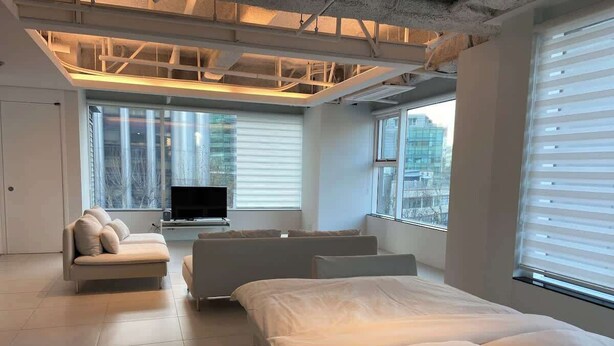 A modern hotel room with a large bed, a sofa, and a TV.