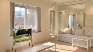 Un salon moderne avec un canapé, une table basse et un téléviseur posé sur un meuble.