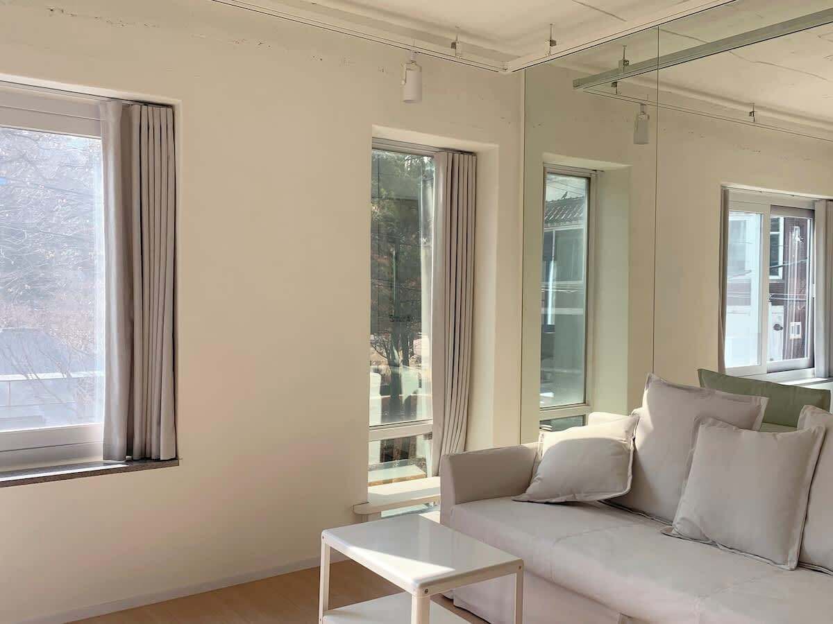 A room with a sofa, a small table, and large windows with curtains.