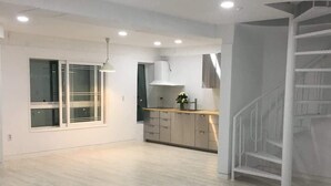 Un vaste espace de vie comprenant une cuisine, un escalier et une grande fenêtre.