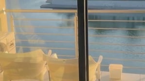 Ein Balkon mit Blick auf ein Gewässer und Gebäude in der Ferne.