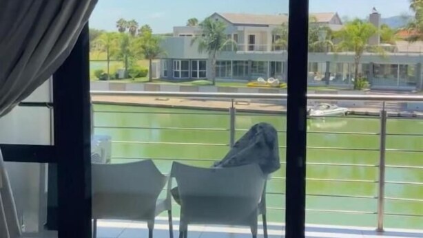 Ein Zimmer mit einer großen Schiebetür, die auf einen Balkon mit Blick auf Grünflächen und Gebäude führt.