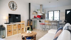 A modern living room with a television, wicker baskets, a round coffee table, and a sofa. - Charming house - near train station - 6 people (Les Sables-d´Olonne)
