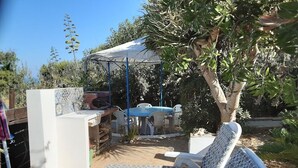 A patio with two lounge chairs, a table, and a covered area with a pool. - Sun Sea Nature b (Sicilia)