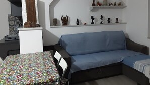A living room with a blue sofa, a patterned table, and shelves with decorative items.
