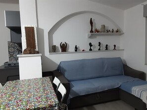A living room with a blue sofa, a patterned table, and shelves with decorative items.
