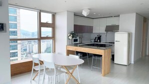 Una cucina moderna con mobili bianchi, un'isola in legno e un'area pranzo con sedie bianche.