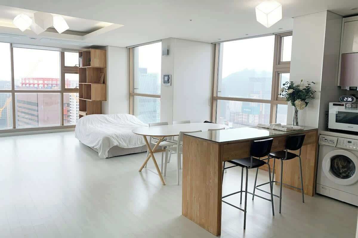 Een modern appartement met keuken, eethoek en een groot raam met uitzicht op een stadsgezicht.