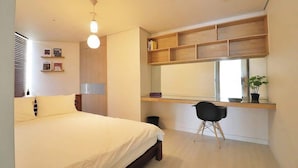 Una camera da letto con un letto, una scrivania con scaffali, una sedia e una finestra.
