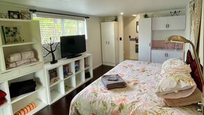 Ein Schlafzimmer mit einem Bett, einem Fernseher, einem Kleiderschrank und einer Sitzecke mit einem roten Sofa.