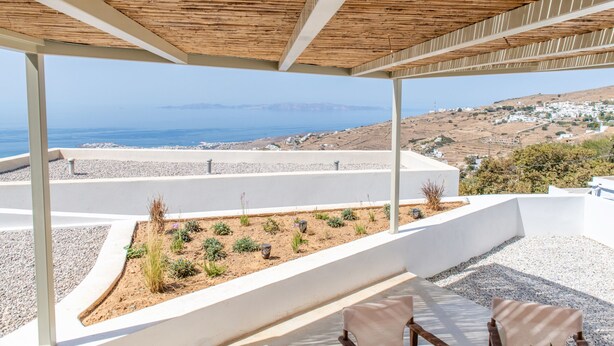 A covered outdoor seating area with a view of the sea and a hillside village. - Blu Dot Tinos by TinosHost (Tinos)