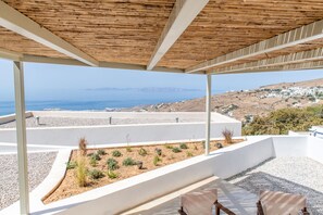 A covered outdoor seating area with a view of the sea and a hillside village. - Blu Dot Tinos by TinosHost (Tinos)