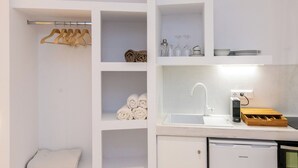 A compact kitchenette with a built-in oven, a sink, and a compact refrigerator. - Blu Dot Tinos by TinosHost (Tinos)