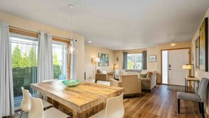 Un vaste espace de vie comprenant une table à manger en bois, des chaises blanches et un canapé.