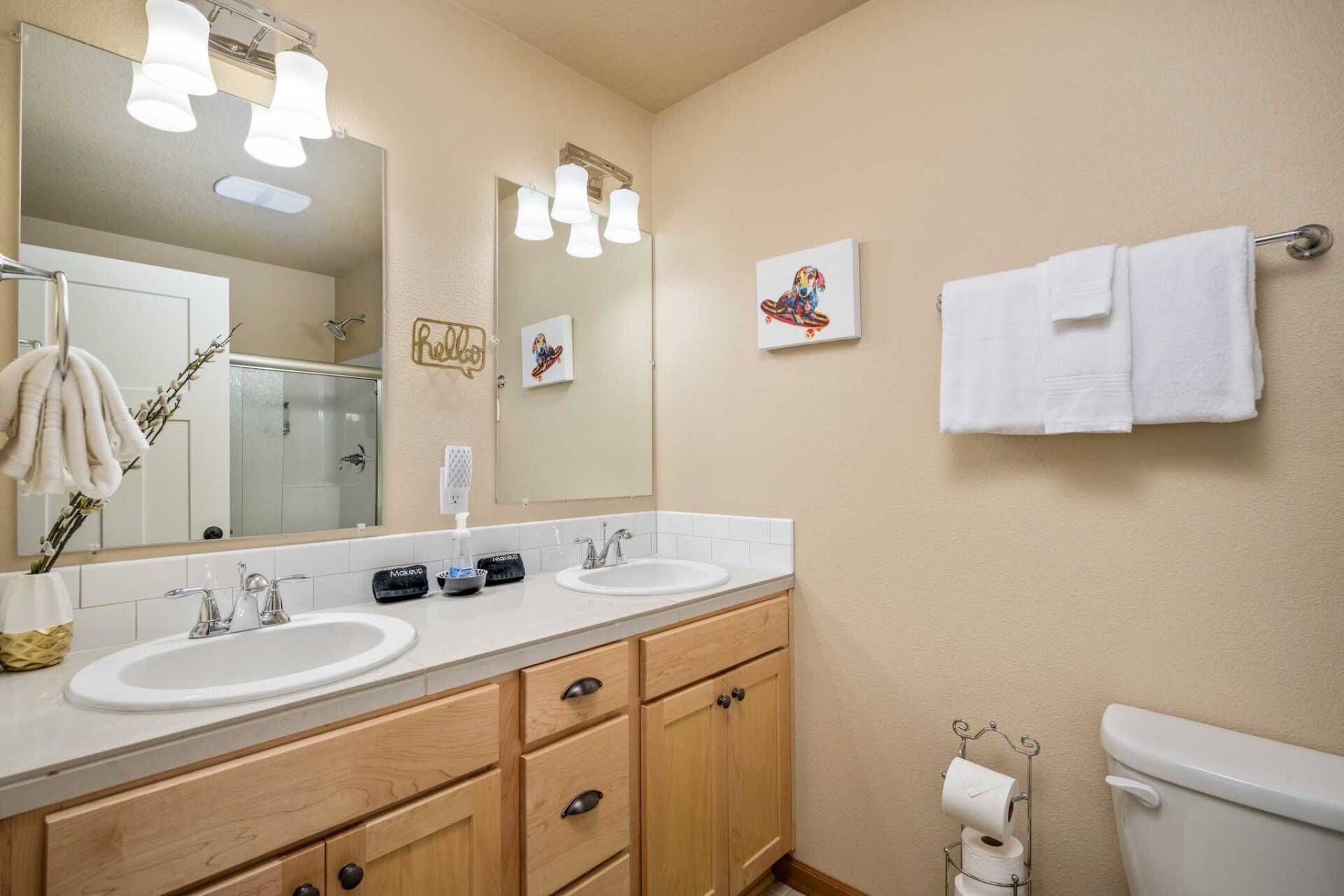 A bathroom with two sinks, a mirror, a towel rack, and a toilet.