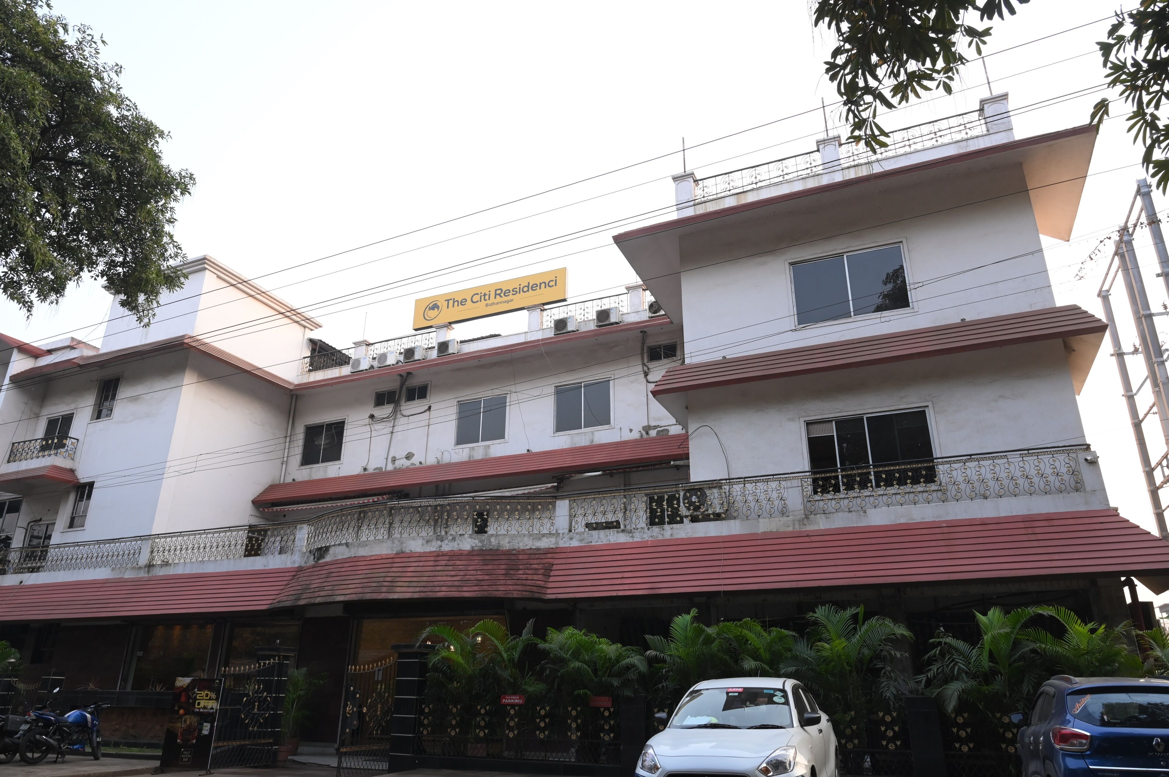 A multi-story building with a sign reading "The Citi Residencies." It features balconies with metal railings, a red roof, and several windows.