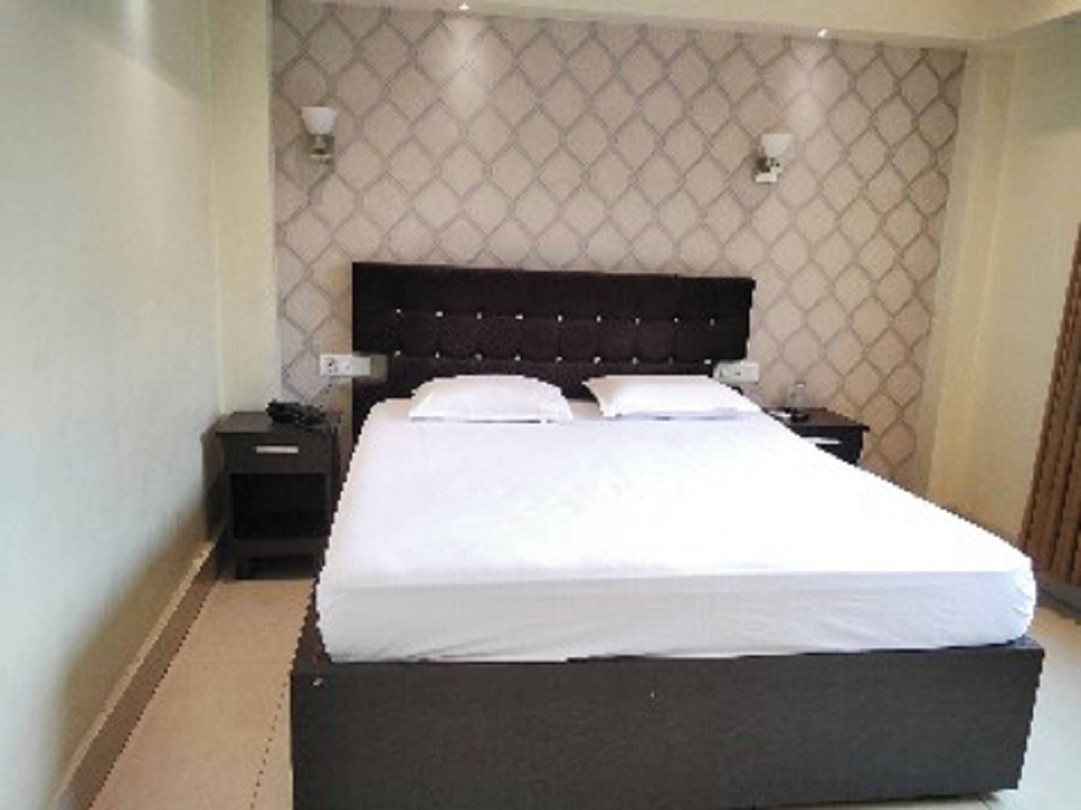 Una cama bien hecha con un cabecero oscuro en una habitación de hotel.