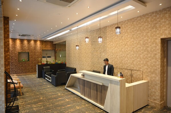 A hotel reception area with a reception desk, seating area, and a patterned wall. - The Citi Residenci Hotel, Bidhannagar (Durgapur)
