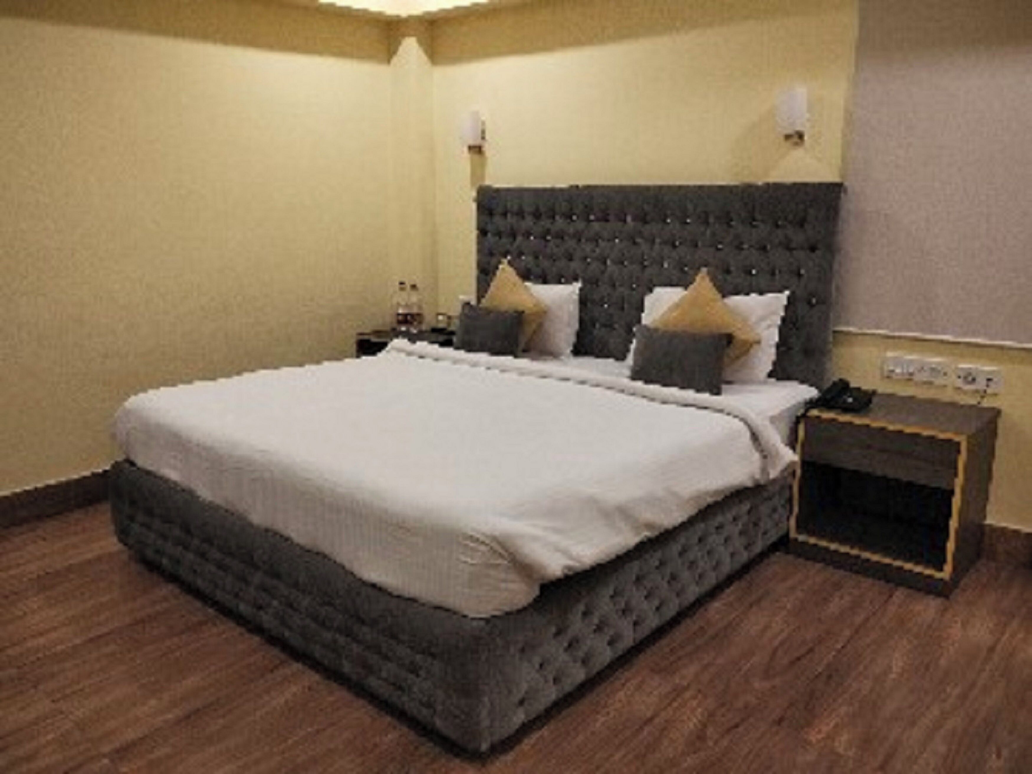 Un dormitorio ordenado con una cama grande, una mesita de noche y un tocador.
