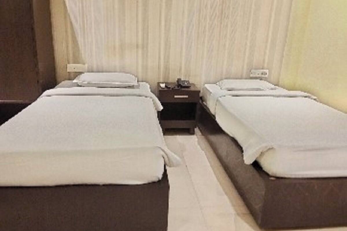 Una habitación de hotel con dos camas individuales, una mesita de noche y otra a la cabecera.