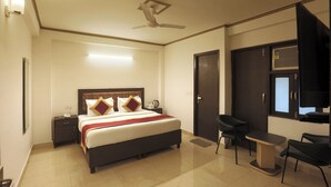 Habitación de hotel con cama, mesita de noche, escritorio, sillas y ventilador de techo.