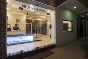 A reception area with a glass facade, a reception desk, and a clock on the wall. - Hotel Dolphin Near IGI Airport  (New Delhi)