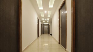 Un pasillo largo y estrecho con suelo de baldosas y puertas de madera a ambos lados.