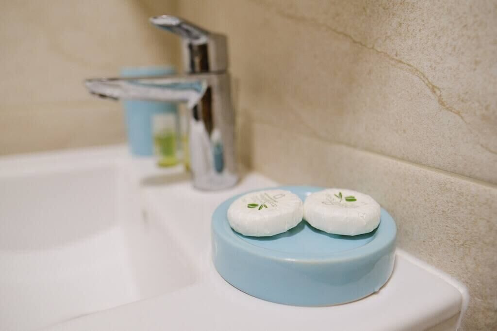 A bathroom sink with a blue soap dish holding two white soaps.