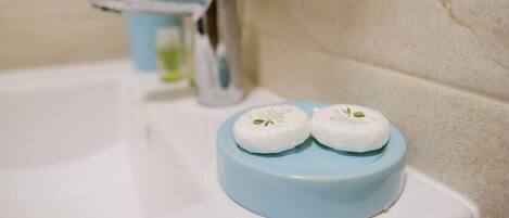 A bathroom sink with a blue soap dish holding two white soaps.