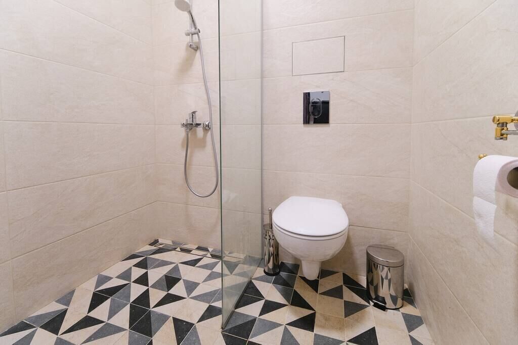 Ein Badezimmer mit Dusche, Toilette und Mülleimer.