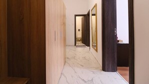 A hallway with a wooden panel wall, a marble floor, and a dark wooden door with a mirror. - Apartment in the city center (Plovdiv)