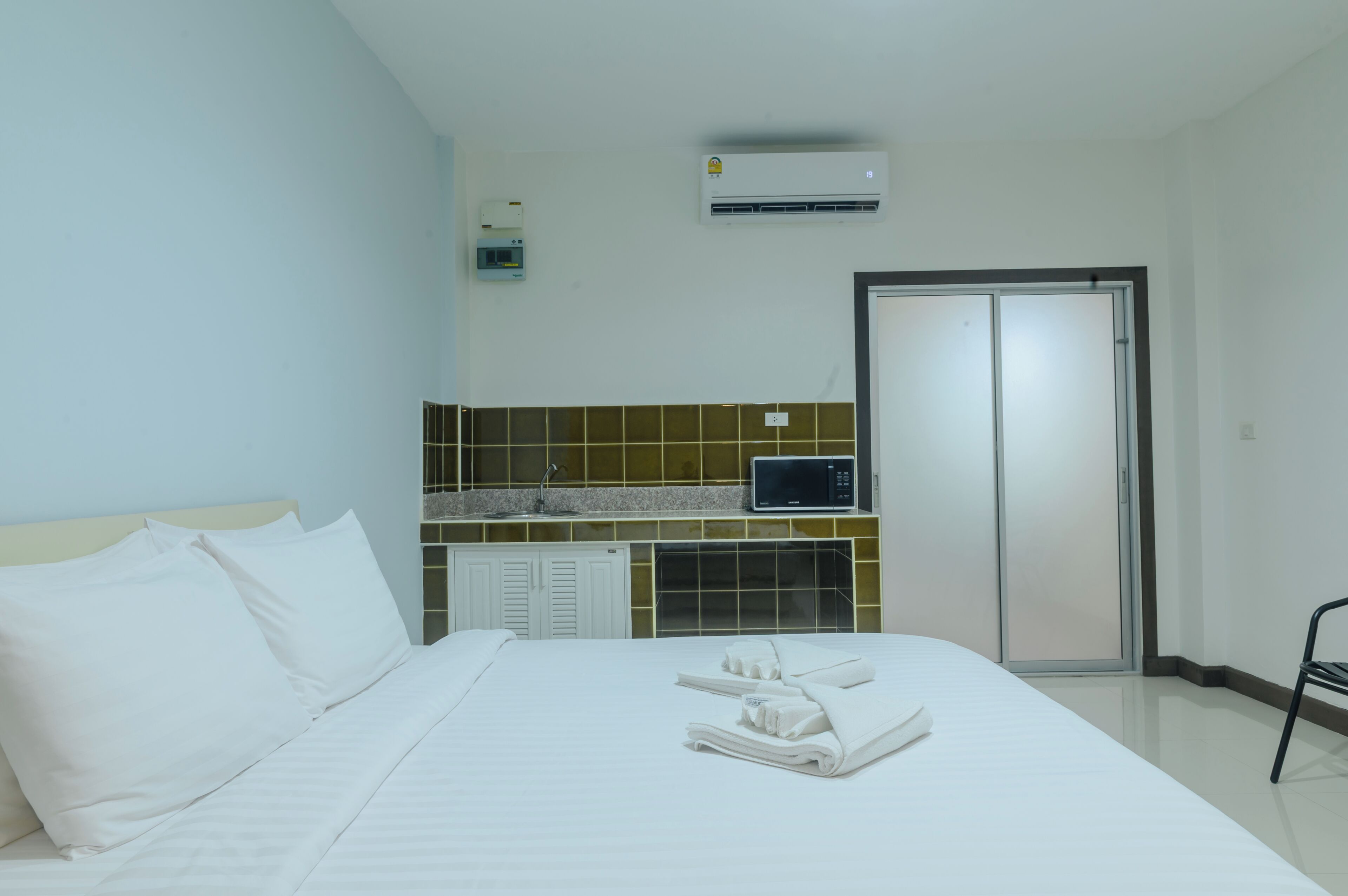 A hotel room with a bed, a TV, a microwave, and a wardrobe.