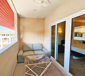 Un balcon avec un canapé, une table en marbre et une vue sur un immeuble.