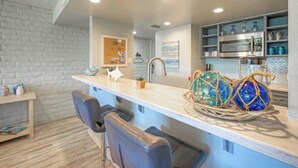 Une cuisine moderne avec un plan de travail blanc, des tabourets de bar et des boules de verre décoratives.