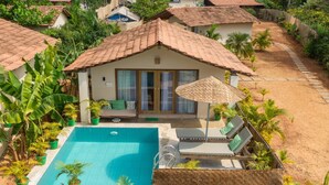 Un área junto a la piscina con piscina, sillas de descanso y una zona de estar cubierta.