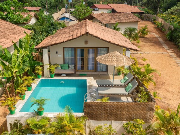 A poolside area with a swimming pool, lounge chairs, and a covered seating area. - Green Leaf Resort (Canacona)