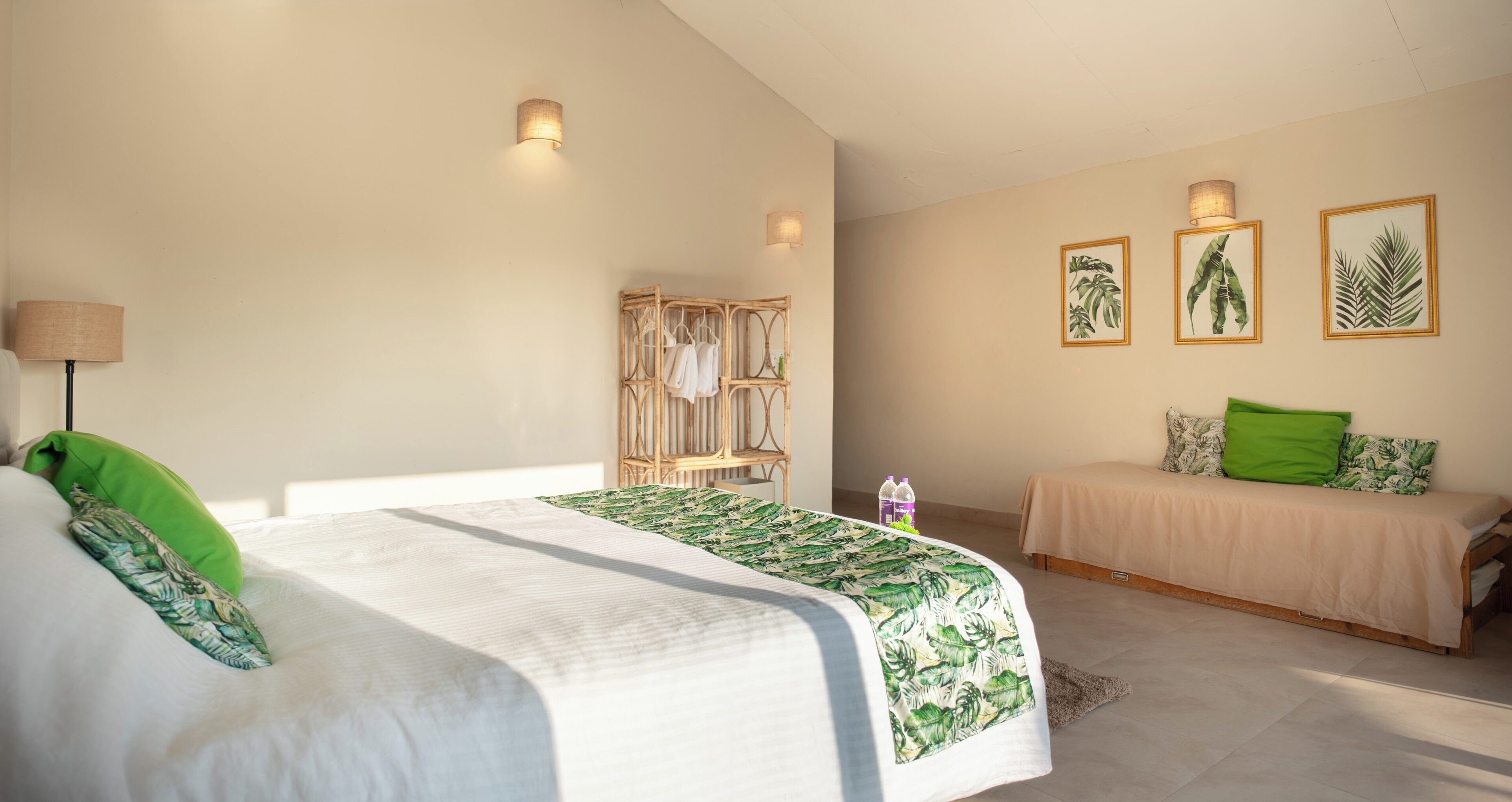 Un dormitorio con una cama grande, una cama más pequeña, un armario y luces fijadas a la pared.
