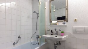 A modern bathroom with a bathtub, a sink, a toilet, and a mirror.