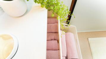 A white storage box with pink towels and a small potted plant.