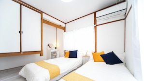 Ein Hotelzimmer mit zwei Betten, einem Schreibtisch und einer Klimaanlage.