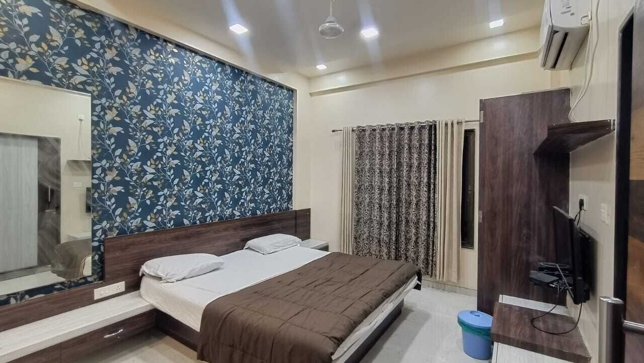 A bedroom with a bed, a mirror, a wardrobe, and a television.