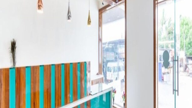 Een moderne receptie met een houten receptiebalie en glazen deuren naar een buitenruimte.