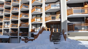 Un hôtel à plusieurs étages, doté de balcons en bois et d’une entrée recouverte de neige.