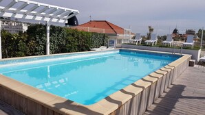 A rectangular pool with a tiled edge, surrounded by a wooden deck. - Terrace Apartment Near the Beach (Cagnes-sur-Mer)